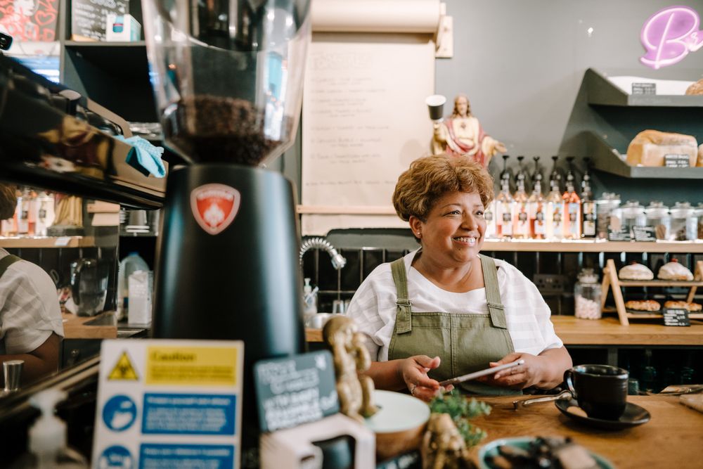 Smiling older Black woman with digital tablet in coffee shop