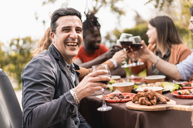 Portrait of a smiling mature man looking at the camera holding a glass of red wine