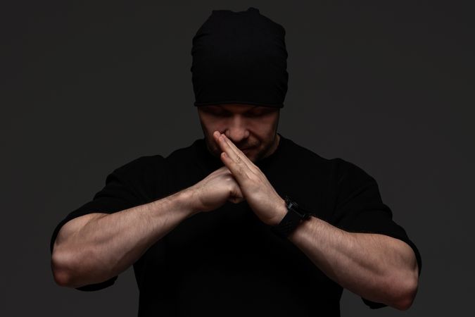 Man in beanie and sweatshirt pressing hands together