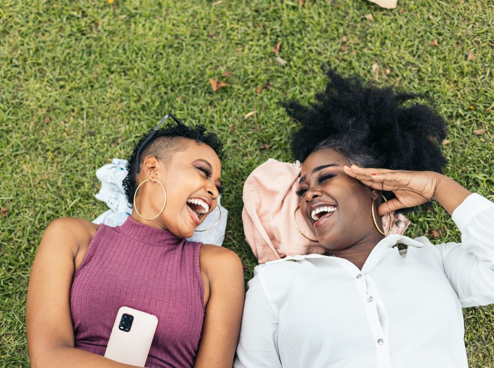 Happy women taking selfies lying on the grass