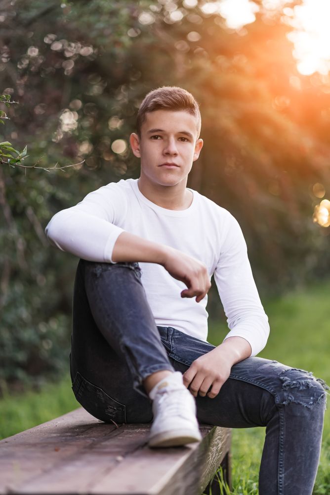 Teenager sitting on park bench looking at camera
