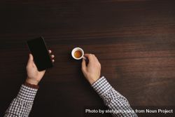 Businessman in plaid shirt checking cell phone with espresso shot bxP1Zb