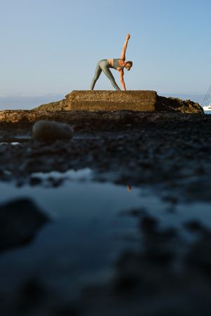 Woman doing yoga in Triangle pose on pier