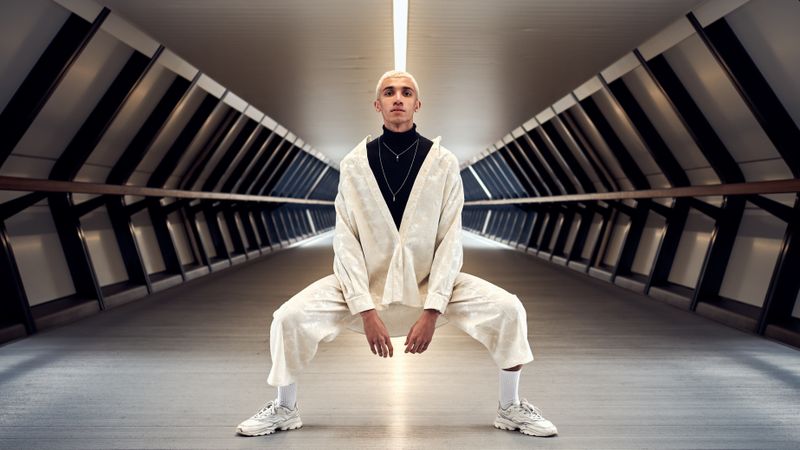 Stylish young man centered in modern symmetrical long corridor