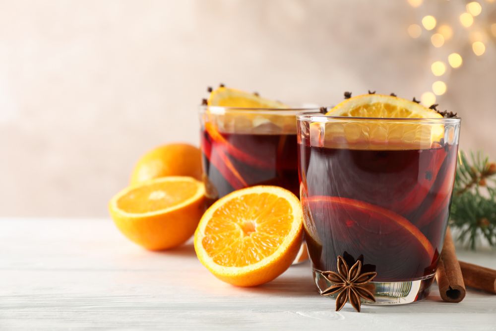 Glasses of tasty mulled wine with orange on wooden background, space for text