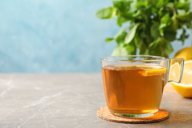 Cup of tea, lemon and mint on grey background, space for text
