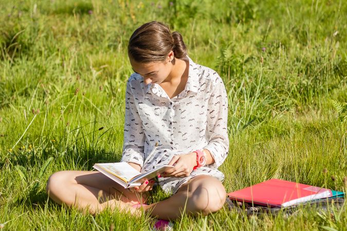 young student reading a book in the park