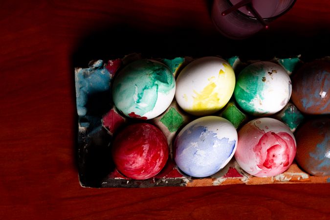 Set of painted Easter eggs in container on table