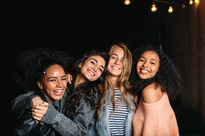 Multi-ethnic group of smiling women embracing on an outdoor patio