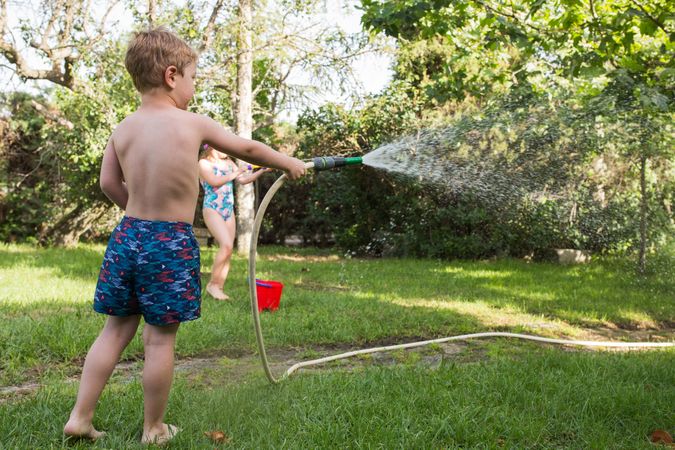 Little kids in swimwear having fun with splashing water