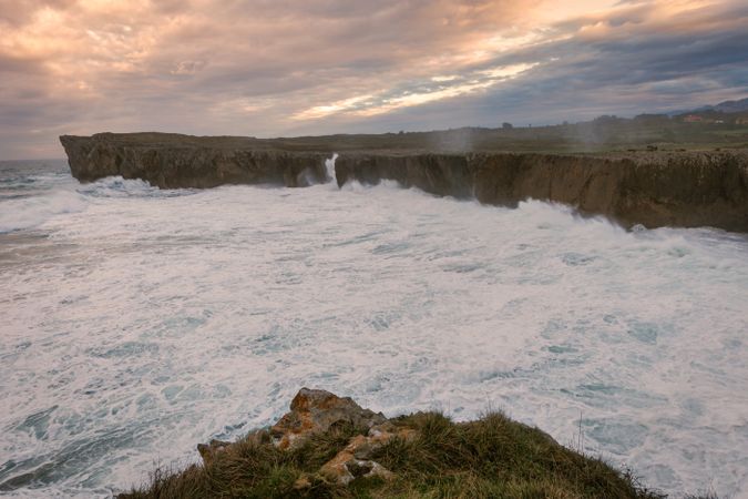 Powerful wave splashing at granite cliff