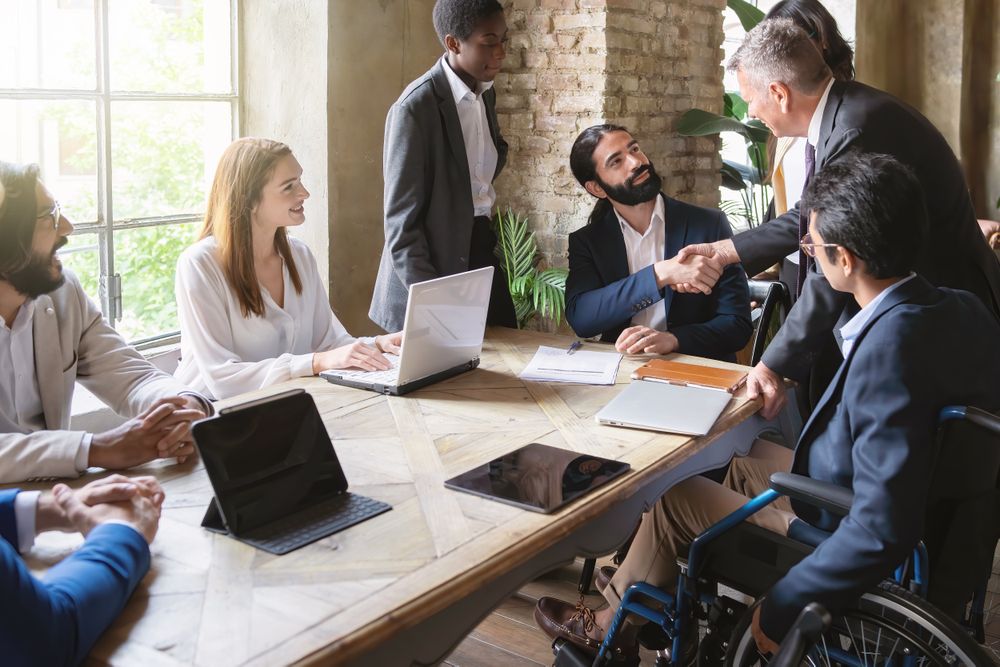 Collaborative businessmen shake handshake at meeting among colleagues