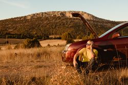 Man leaning in broken car in countryside