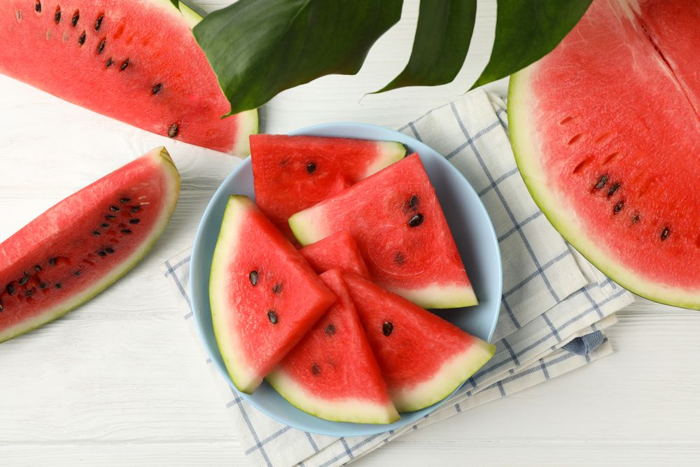 Composition with plate of fresh watermelon on wooden background, top view