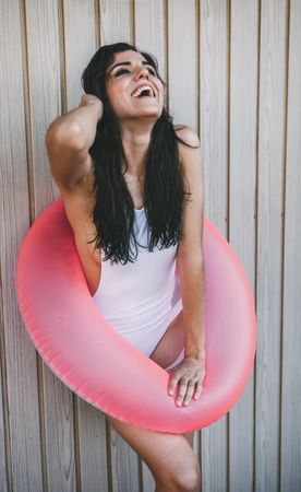 Woman with a swimming ring posing by white wooden fence