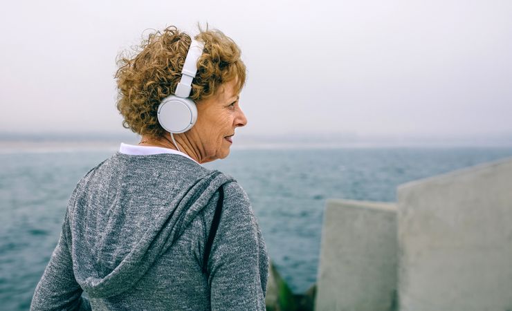 Mature sportswoman with headphones looking aside