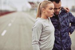Fit woman standing beside her boyfriend on an open road