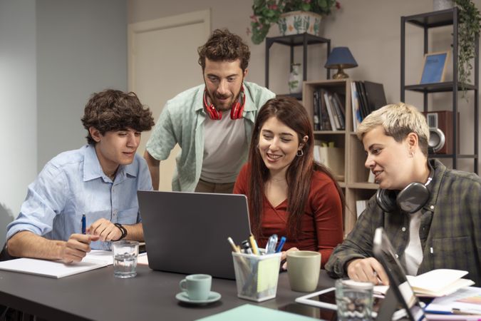 Young friends collaborating on laptop in modern home office smiling and brainstorming session
