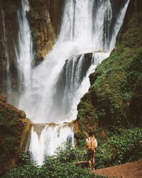 Woman in valley with amazing waterfall