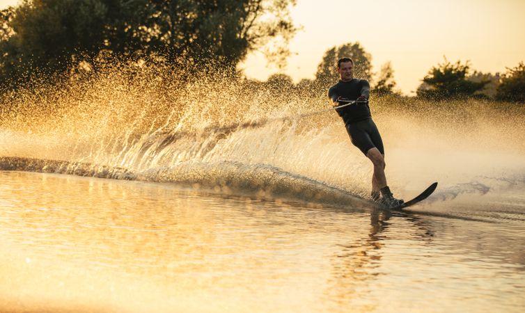 Fit male water skiing with single ski