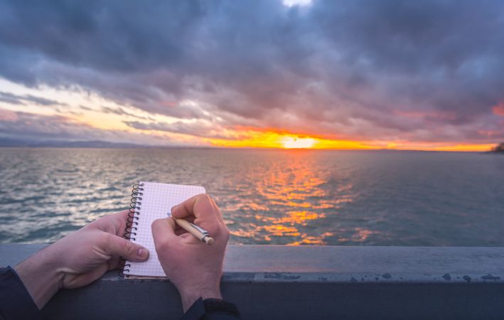 Writing on a notebook at sunset