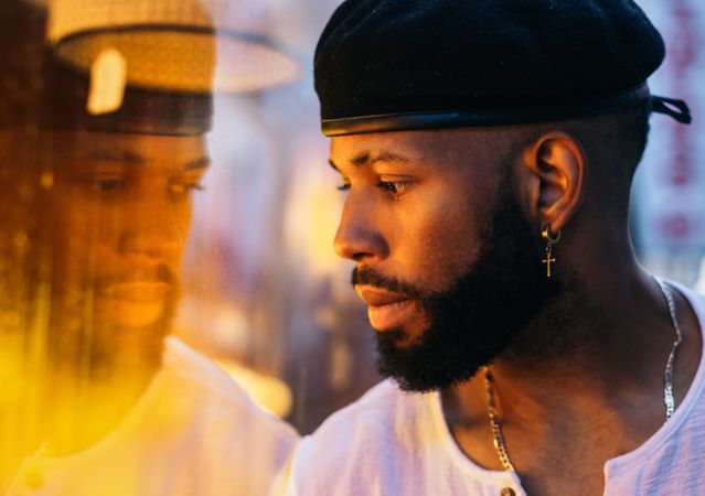 Black man near a glass. reflection and warm light