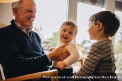 Grandfather enjoying time with his grandsons at home 0LARE5