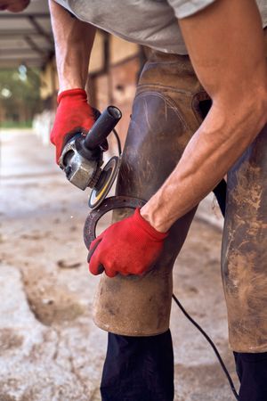 Blacksmith changing horseshoe to the leg of a horse using bald lime hammer pliers