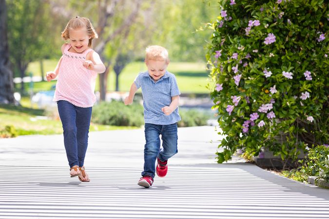 Young Sister and Brother Having Fun Running At The Park