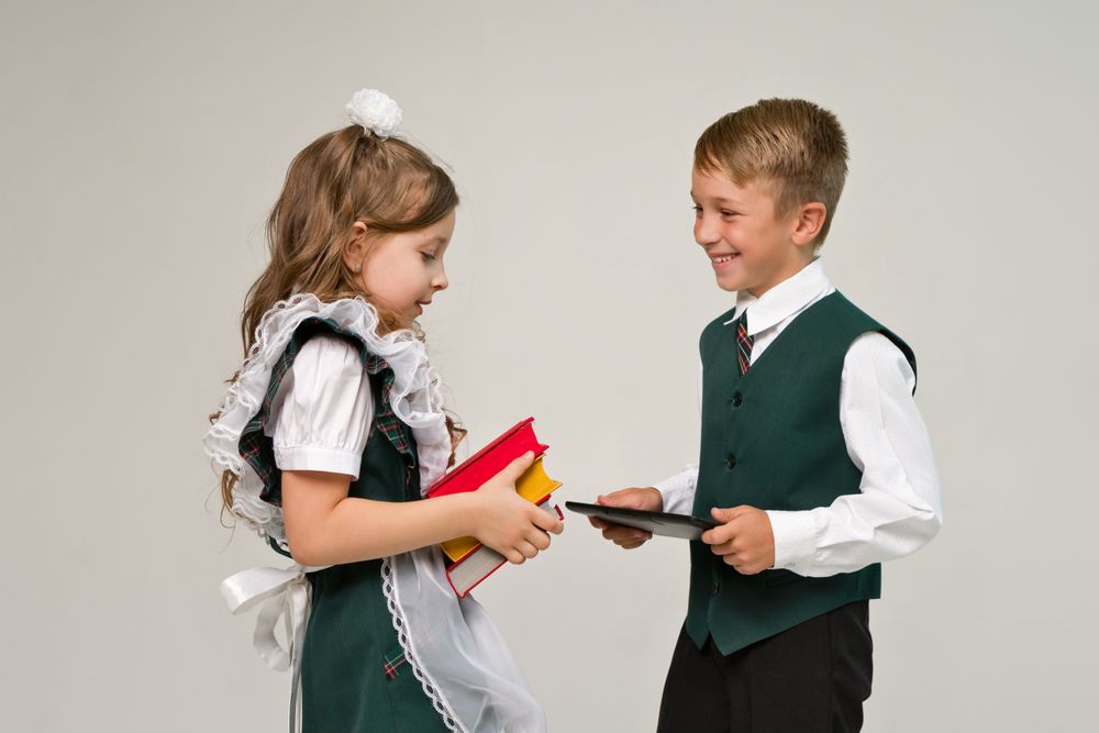 Portrait elementary school students in uniform with books and tablet