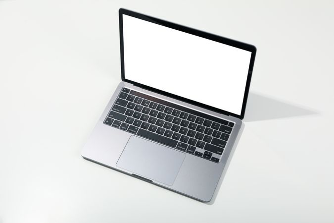 Opened silver laptop at angle with mockup screen on desk