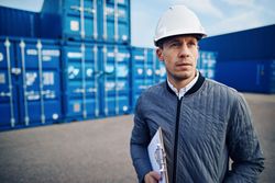 Man in hardhat on building site with clipboard