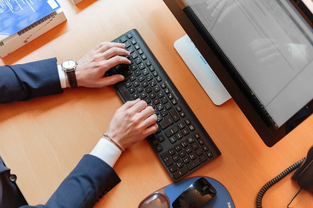 Cropped image of a person in dark blazer using computer keyboard