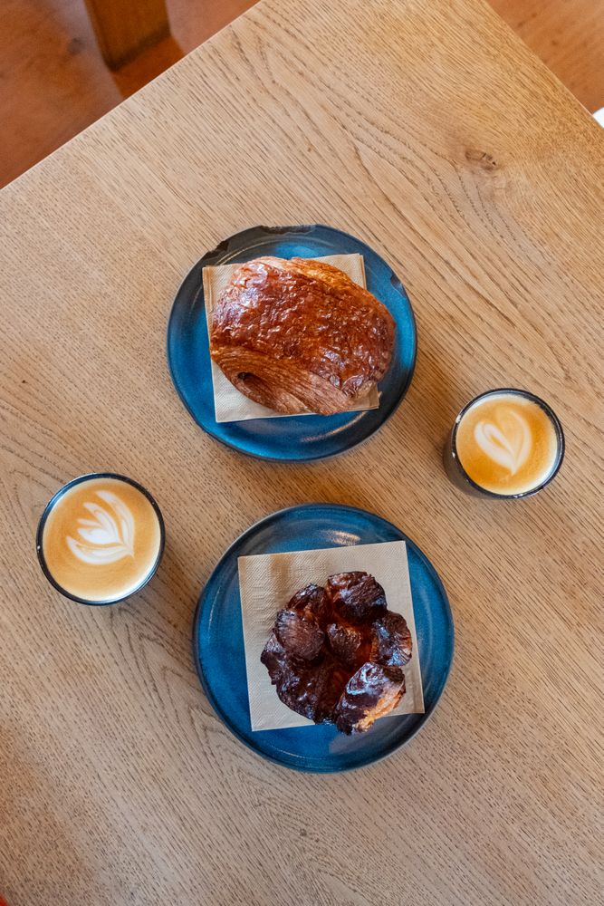 Top view of breakfast roles and cappuccinos on wooden table