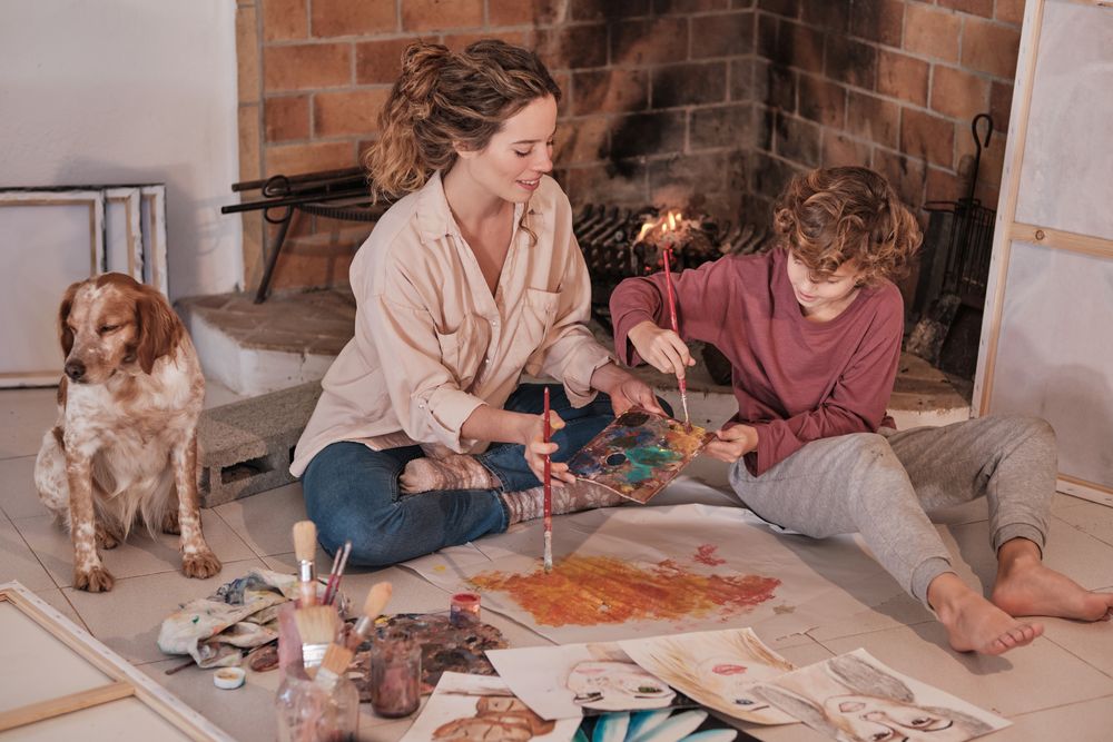 Child enjoying free time at home while painting with mom