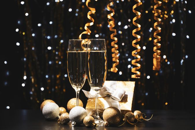 Christmas baubles and champagne glasses on blurred background, copy space