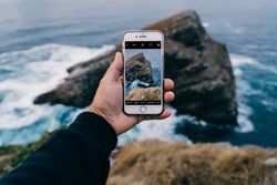 Person taking photo of cliffs and sea