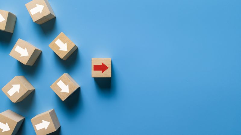 wooden blocks with irregular arrows and one red arrow pointing right direction isolated on blue background.