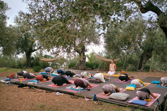 Faceless women doing Extended Child asana in countryside