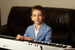 Smiling young boy playing the piano.