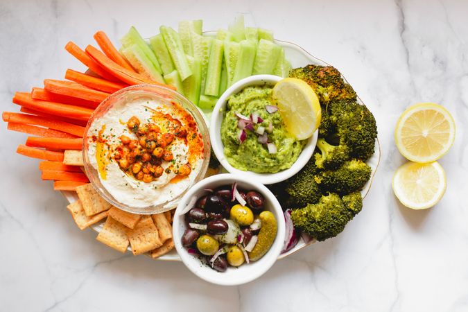 Tasty hummus and sauces decorated with bright cut vegetables on table