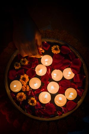 Top view of hand putting a candle on tray of roses and flowers