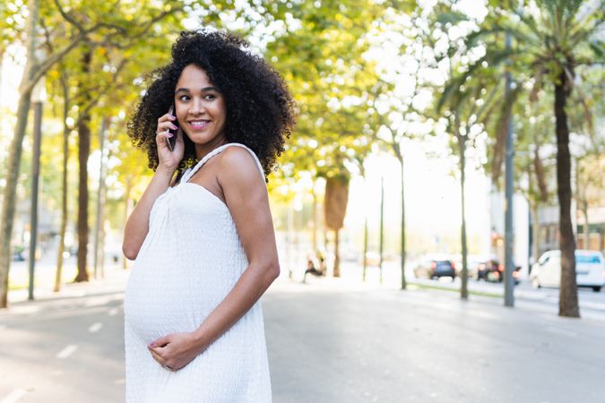 Smiling Black pregnant woman talking on smartphone