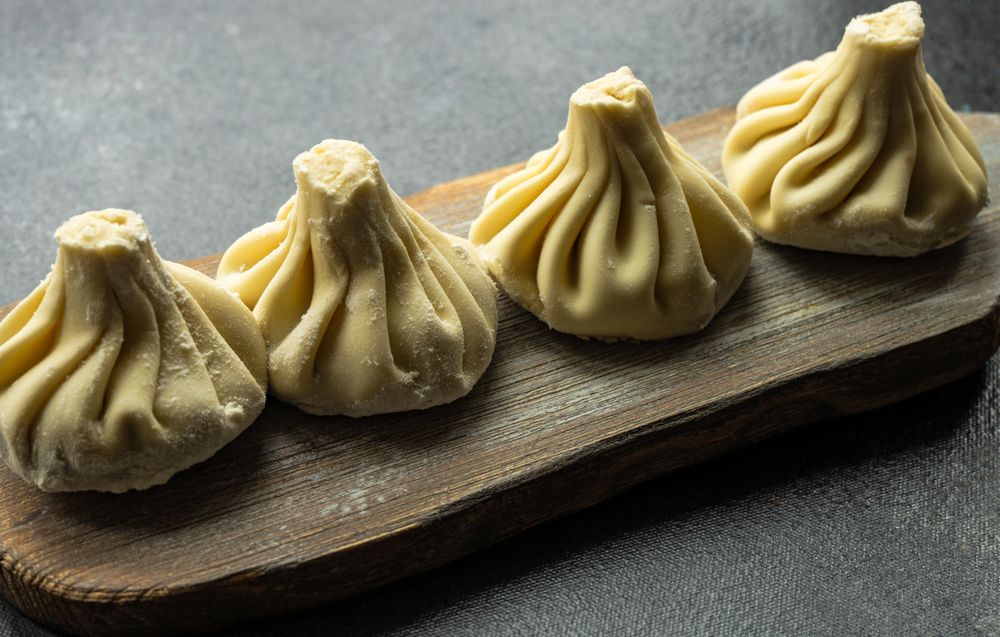 Traditional Georgian khinkali dumplings served on wooden board on counter