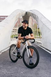 Cheerful man with bicycle standing on footbridge