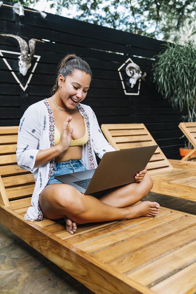 Relaxed woman using laptop while resting on deck chair
