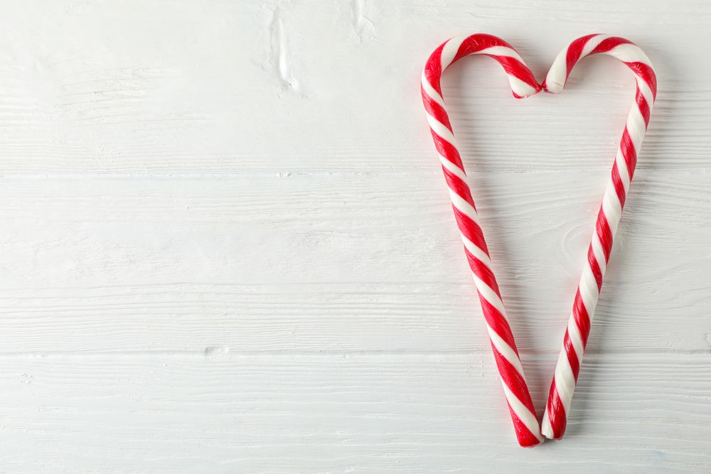 Sweet candy canes on wooden background, space for text