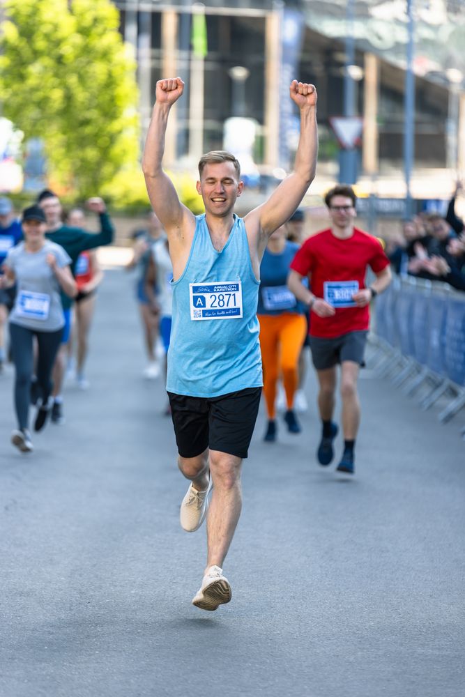 Athletic Young Man Crossing the Finish Line in a City Marathon During the Day.