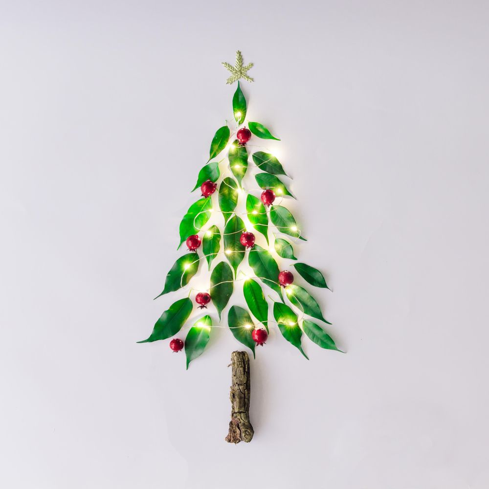 Christmas tree topped with star with lights made of leaves, berries and branch