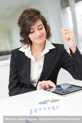 Female in business attire reviewing data and charts in a bright office 0KX8Y5